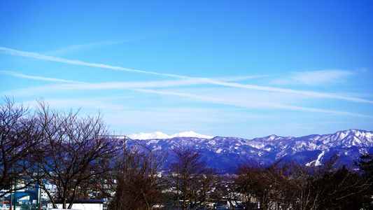 光り輝く雪山と飛行機雲の軌跡
