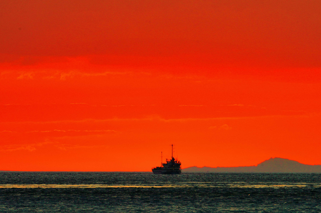 日没時の朱色の空と船
