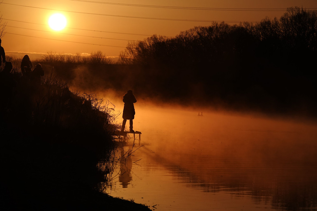 朝陽と川霧と女性
