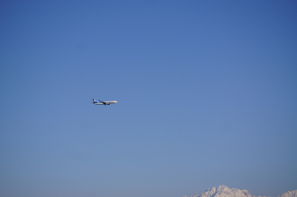 立山連峰と着陸する飛行機
