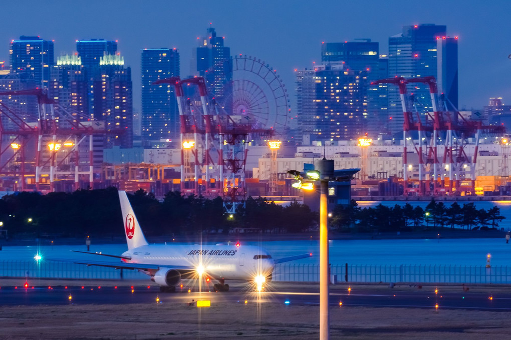 都会の夜景を背景に羽田空港16Lで離陸を待つB767