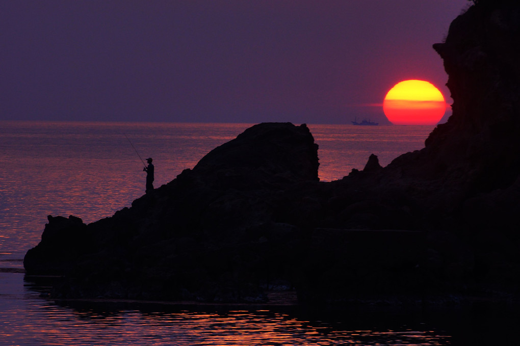 釣り人と夕陽と漁船