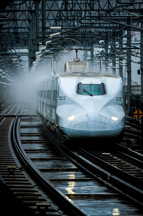 雨の中を駆け抜けて行く新幹線