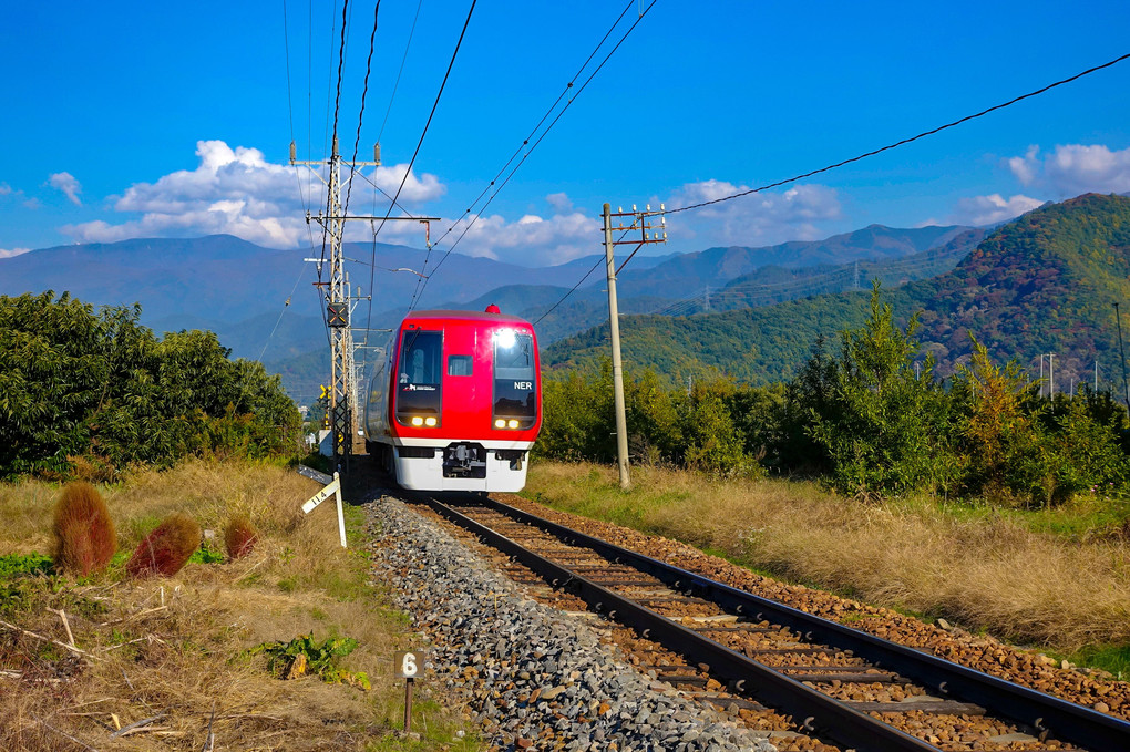 志賀高原の山並みを背に走る長野電鉄2100系特急「スノーモンキー」号