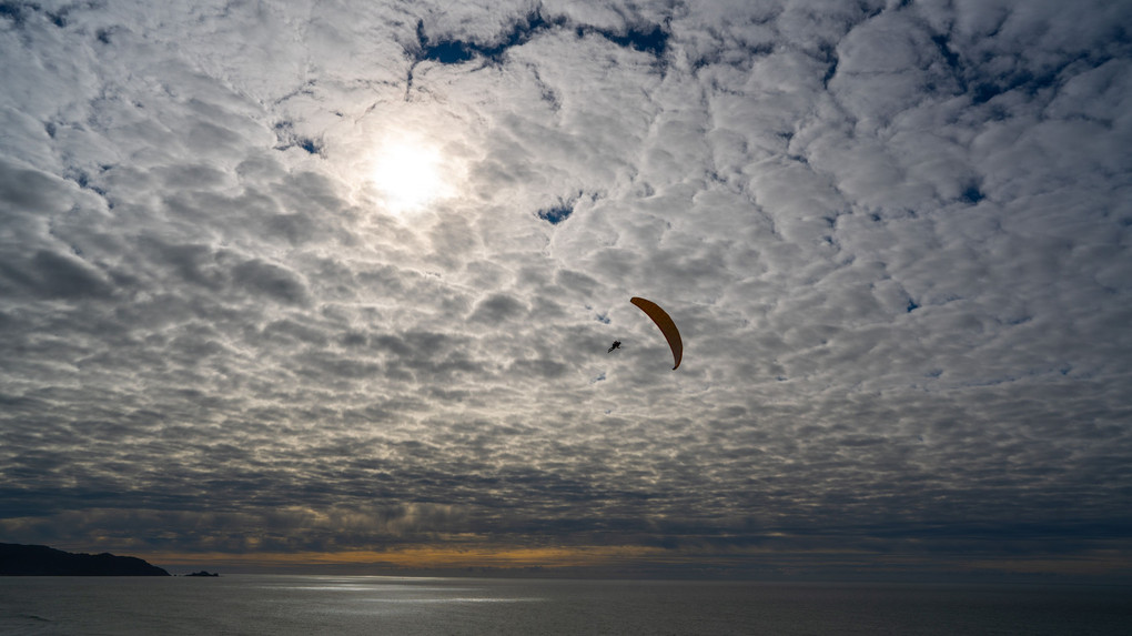 まだら雲に飛ぶパラグライダー