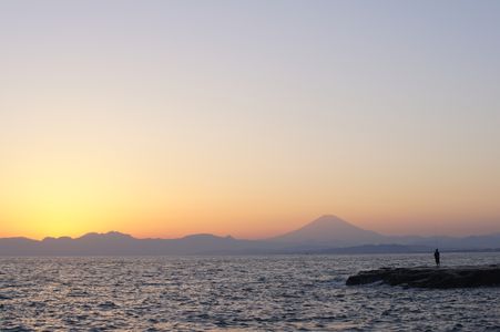 海の向こうに沈む太陽の横の富士山