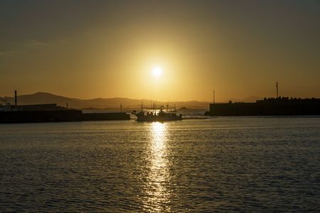 夕日に照らされたイカ釣り漁船